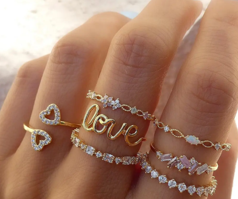 Gold-toned stackable rings with hearts, flowers, and cubic zirconia, celebrating love, joy, and positivity in a whimsical style.