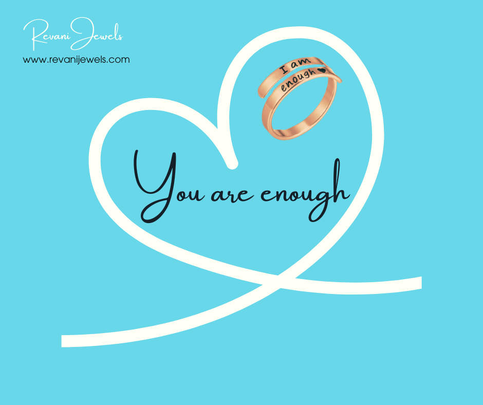 Rose gold ring with 'You are enough' text on a blue background with a white heart.