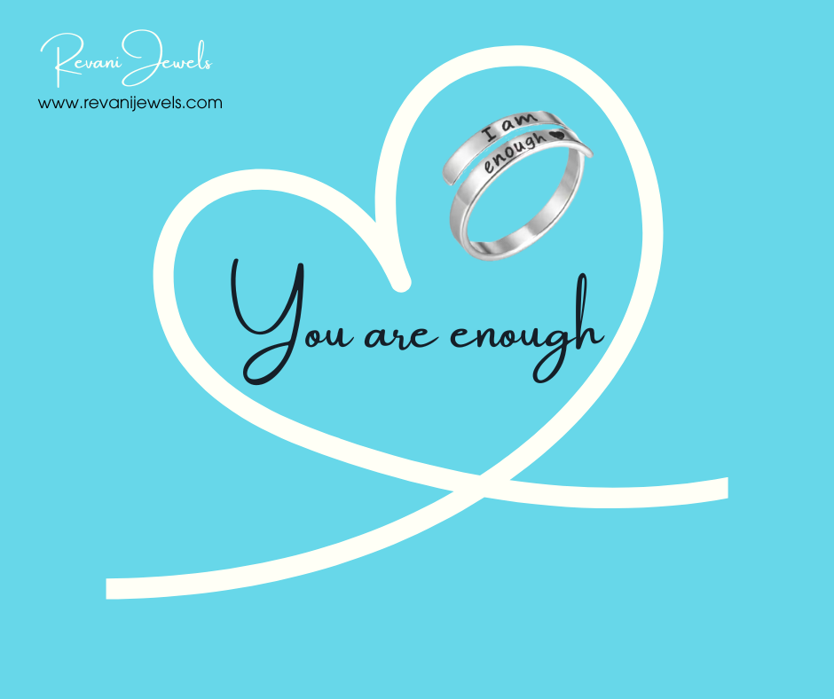 Silver ring with 'I am enough' engraving on a heart-shaped white ribbon against a blue background, featuring Revani Jewels branding.