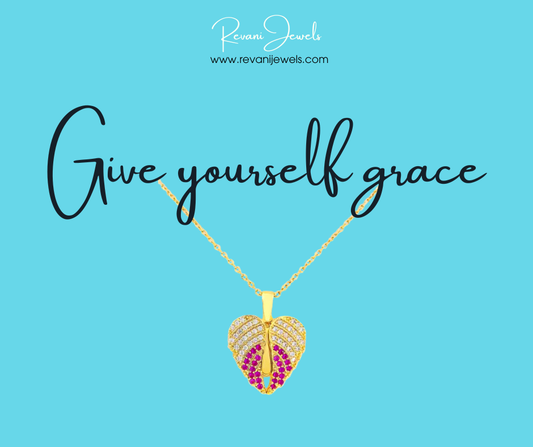 Gold necklace with a heart-shaped pendant on a blue background with 'Give yourself grace' text and Revani Jewels branding.