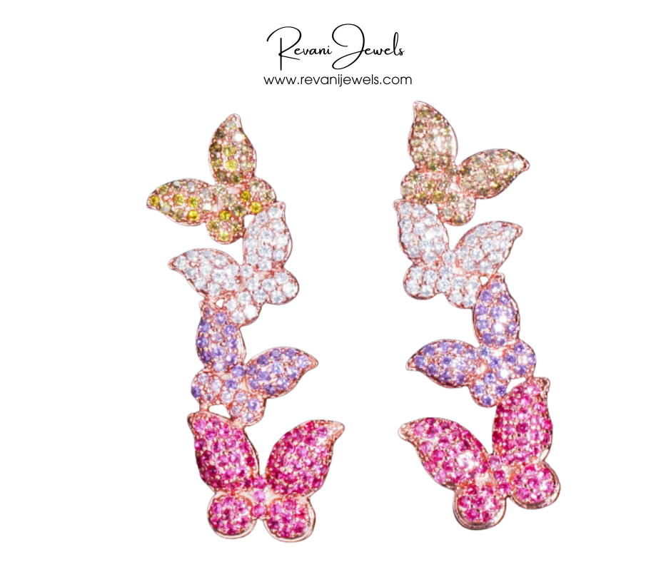 Butterfly-shaped earrings with pink and purple gemstones on a white background, branded as Revani Jewels.