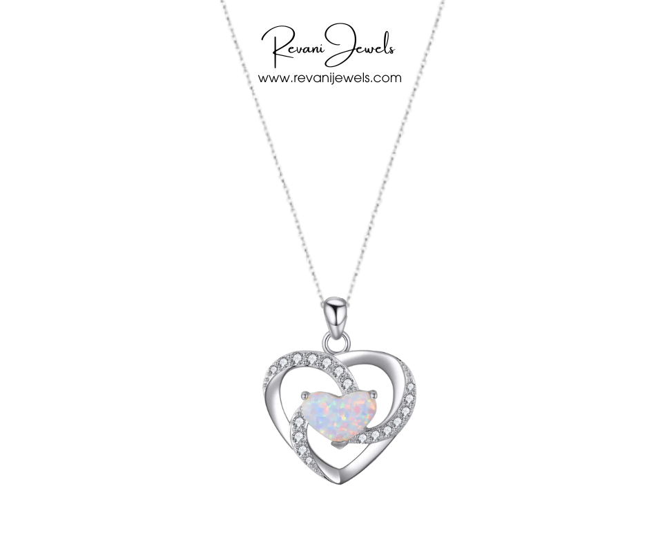 Heart-shaped pendant with a central gemstone on a white background, branded as Revani Jewels.