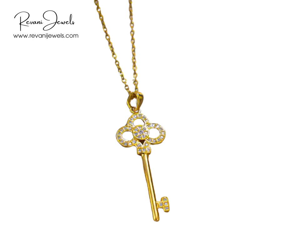 Gold key-shaped pendant necklace on a white background with Revani Jewels branding.