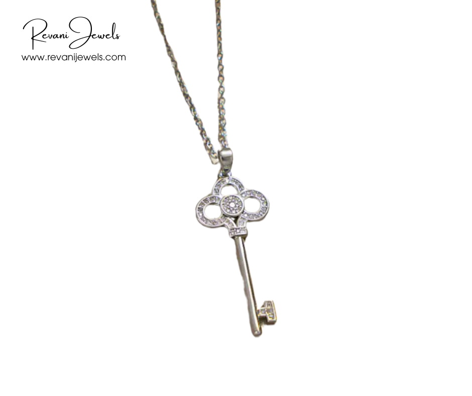 Silver key-shaped pendant necklace with gemstones on a white background, branded 'Revani Jewels'.