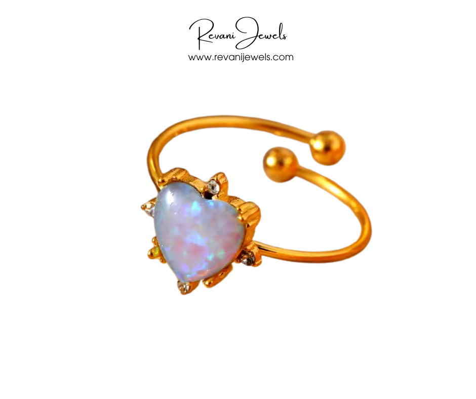 Gold ring with a heart-shaped opal stone on a white background, branded 'Revani Jewels'.