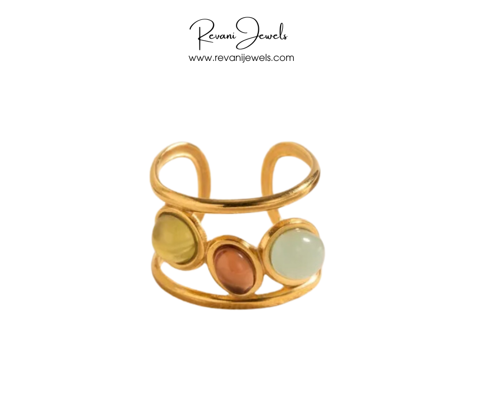 Gold ring with three colored stones on a white background, branded as Revani Jewels.